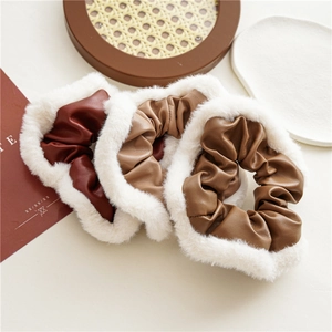 Detailed view of three PU leather and white faux fur scrunchies in autumn colors