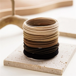 Detail shot of high-elastic seamless hair ties in neutral earth tones on stone texture