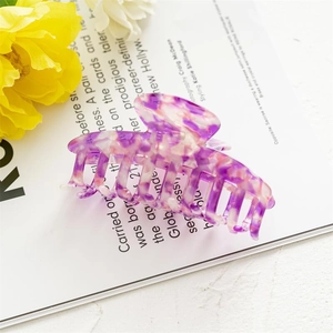 Detailed view of large purple marble acetate hair claw clip on a magazine background