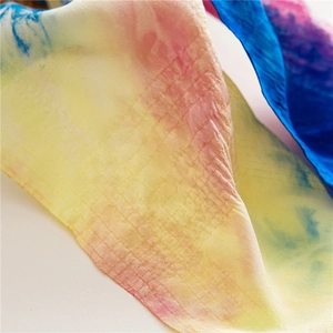 Macro de la texture du tissu tie-dye avec des motifs de grille jaunes, roses et bleus