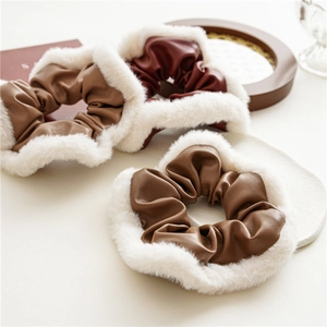 Detail of brown and wine red PU leather hair scrunchies with white faux fur trim