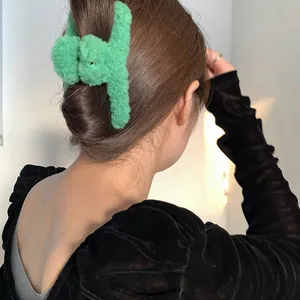 Gros plan d'une pince à cheveux en peluche verte fixant les cheveux longs en chignon chic