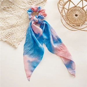 Détail d'un chouchou tie-dye rose et bleu avec de longs rubans fluides en mousseline