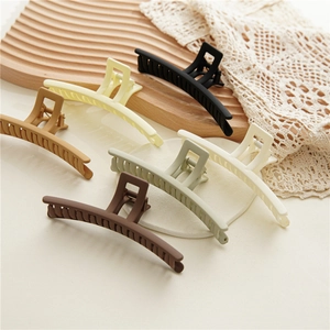 Collection of six elegant matte hair claws in various colors displayed on a wood tray