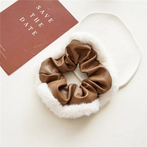 Detailed close-up of brown PU leather and white faux fur patchwork scrunchie