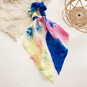 Vue détaillée du chouchou en tissu tie-dye avec de longs rubans sur fond de dentelle douce