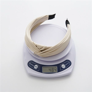 Dettaglio del cerchietto beige in pelle PU con nodo intrecciato e peso leggero di 48g