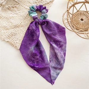 Détails de la texture du chouchou en tissu tie-dye violet avec de longs rubans élégants