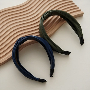 Dettaglio di cerchietti in pelle PU con nodo incrociato in blu navy e verde scuro opaco
