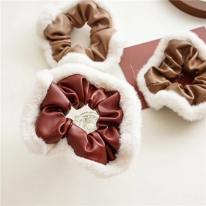 Close-up of PU leather scrunchies in brown and burgundy with white faux fur trim