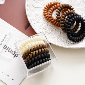 Close-up of 6 durable matte spiral hair ties in assorted colors with acrylic storage box