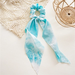 Vue détaillée d'un chouchou en tissu tie-dye avec de longs rubans et une texture plissée