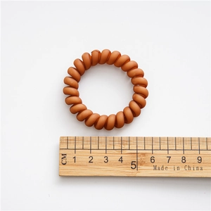 Brown matte spiral hair tie with a 5cm outer diameter shown on a wooden ruler