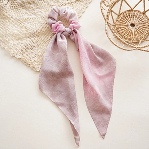 Détail d'un chouchou long dégradé avec rubans sur un fond de couleur crème élégant