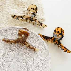 Drei Haarklammern aus Acetat mit Leopardenmuster auf elegantem Spitzenhintergrund