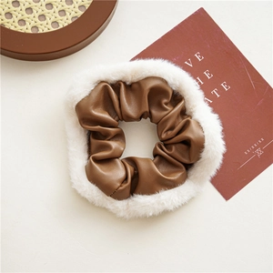 Close-up of brown PU leather scrunchie with soft white faux fur trim for autumn hair style