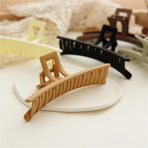 Close-up of large matte hair claw clips in elegant Morandi colors on a white plate