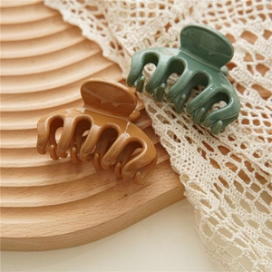 Detail of caramel and olive green glossy resin hair claw clips on a wooden tray
