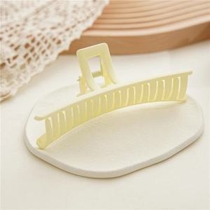 Close-up of large matte cream hair claw clip with strong metal spring and multi-tooth design