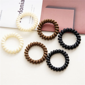 Detail of six durable matte spiral hair ties in beige brown and black colors