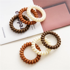 Close-up of matte spiral hair ties in brown and cream shades on a stylish magazine
