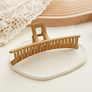 Macro shot of large matte beige shark hair clip on an elegant stone tray display