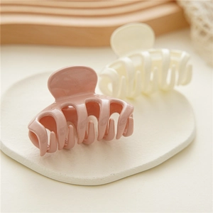 Detail of wavy spiral hair claws in dusty pink and cream white on a white tray