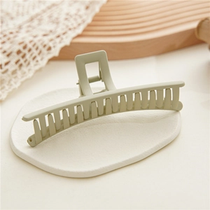 Detail view of large matte light green claw clip for thick hair shown on a white display board