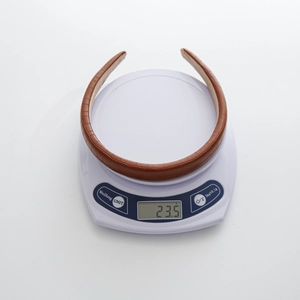 Detailed view of brown crocodile texture headband on scale weighing 23.5 grams