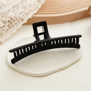 Macro shot of elegant matte black hair claw clip on a textured stone surface display