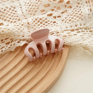 Detail of a soft pink matte hair claw clip on a decorative wooden tray with lace fabric