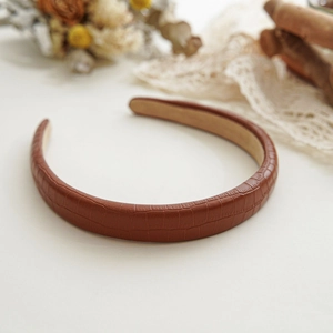 Detailed view of brown faux leather headband with snakeskin texture and soft velvet lining