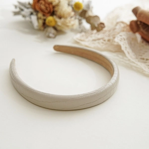 Close-up of beige faux crocodile leather padded headband with suede inner lining