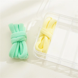 Close-up of pastel mint green and cream yellow high elastic hair ties in a storage box