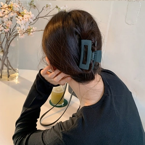 Grande pince à cheveux mate vert foncé portée sur cheveux bruns dans un cadre raffiné