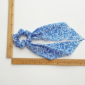 Close-up of blue floral satin scrunchie with long ribbons measured by wooden rulers