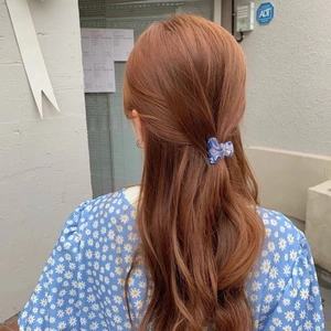 Pince à cheveux papillon en acétate marbré bleu sur cheveux bruns ondulés dehors