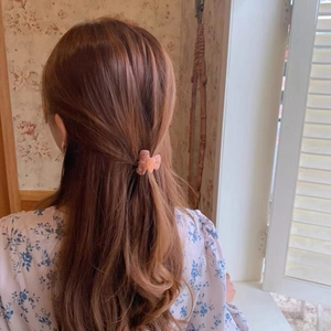 Détail d'une mini pince à cheveux en acétate rose marbré pour une coiffure attachée
