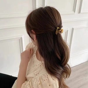 Détail d'une mini pince à cheveux en acétate ambré portée par un mannequin pour un look chic