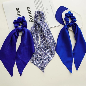 Detailed flat lay of three royal blue satin scrunchies with long silk scarves on white
