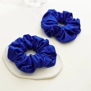 Détail de deux chouchous en satin bleu avec plis élastiques sur un socle en céramique