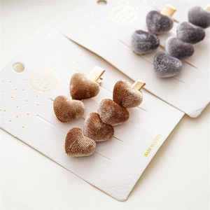 Primer plano de pinzas para el cabello de terciopelo con corazones en cartón blanco