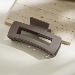 Détail de la pince à cheveux rectangulaire café mat sur support en marbre