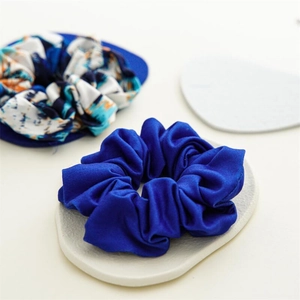 Détail de chouchous en soie bleue et tie-dye sur un support d'exposition épuré