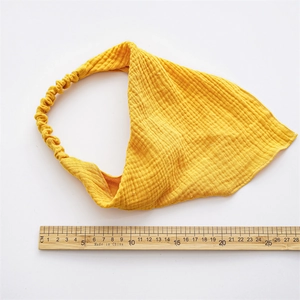 Detail view of yellow ginger crepe fabric headscarf with elastic band on white background