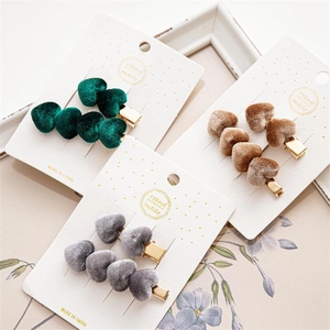 Detalle de horquillas de terciopelo con forma de corazón en verde, marrón y gris con clip de metal