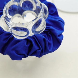 Vue détaillée d'un chouchou en satin bleu roi posé sur un support en verre