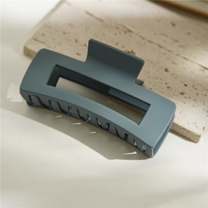 Vue détaillée de la pince à cheveux rectangulaire bleu-gris mate sur pierre