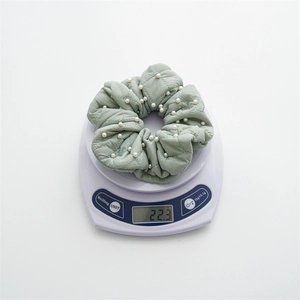 Weight display of a light green quilted scrunchie with pearls on a digital scale