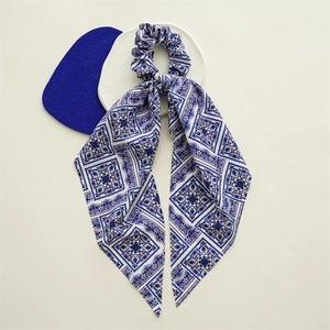 Detail of blue and white geometric floral satin scrunchie with long scarf ribbons